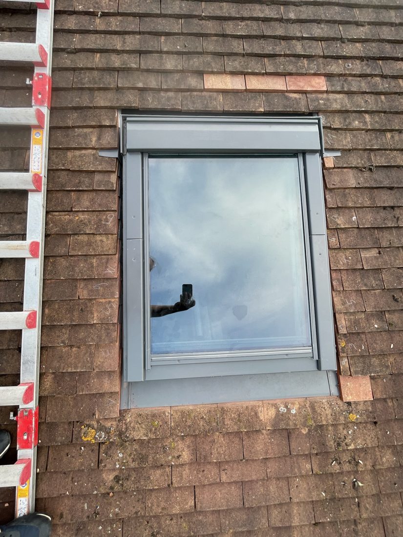 Fenêtre de toit posée avec son raccord en zinc sur une couverture en tuiles dans l'Essonne