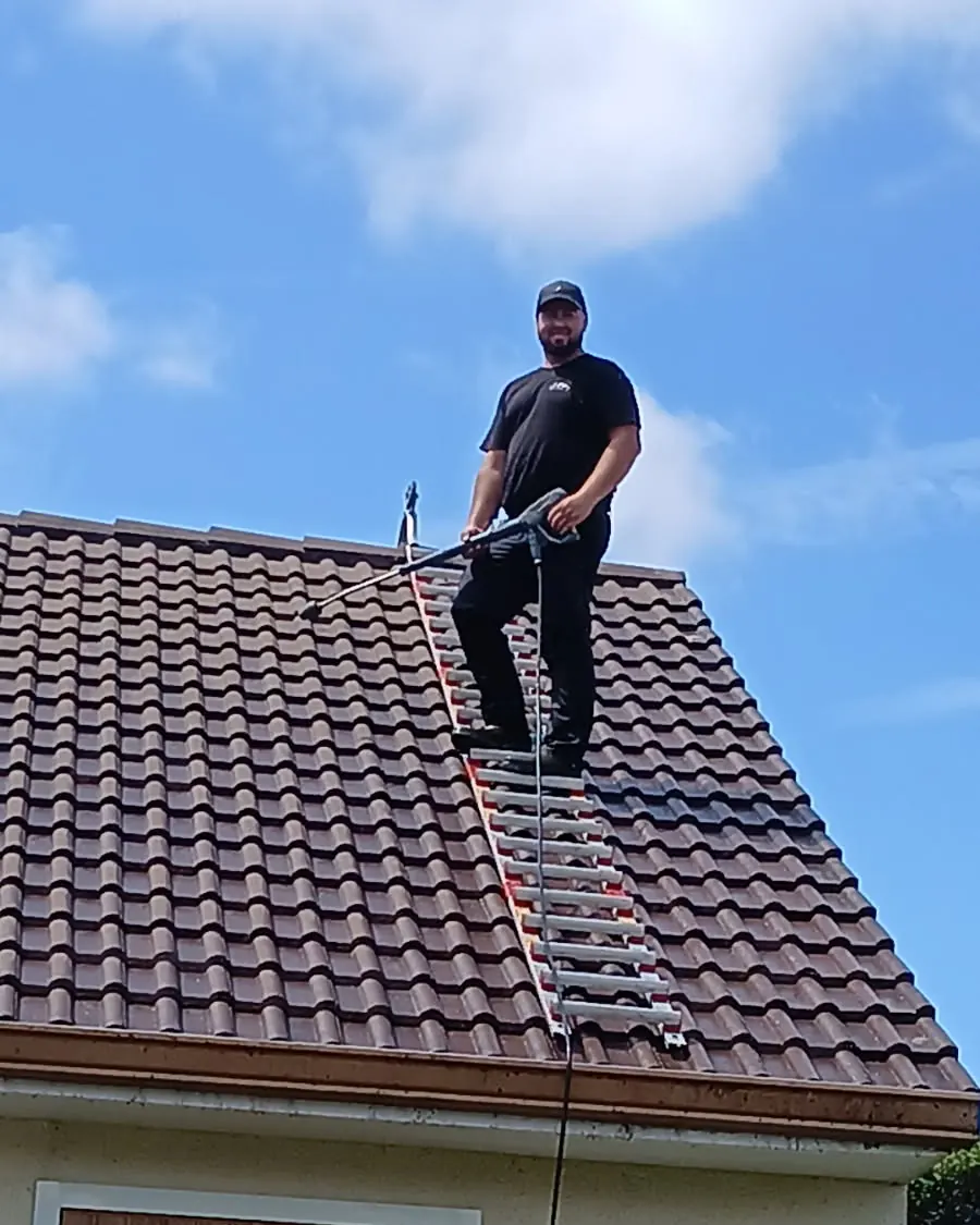 Robert Daniel, couvreur, pendant le nettoyage d'une toiture en tuiles dans l'Essonne