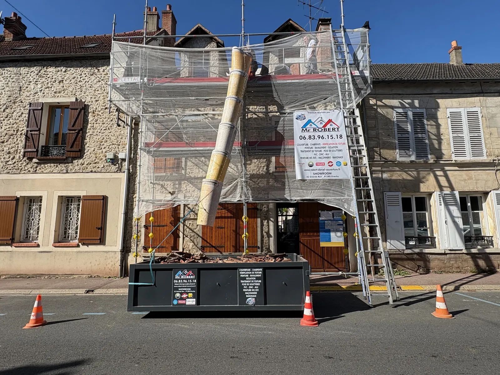 Échafaudage et benne devant une maison en pierre du centre d'Étréchy pendant la réfection de sa toiture