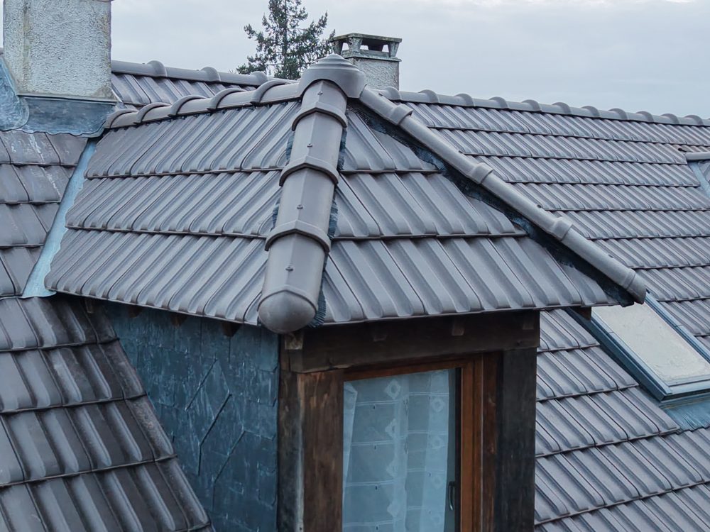 Joues en zinc et faîtage d'un chien-assis sur une toiture en tuiles dans l'Essonne